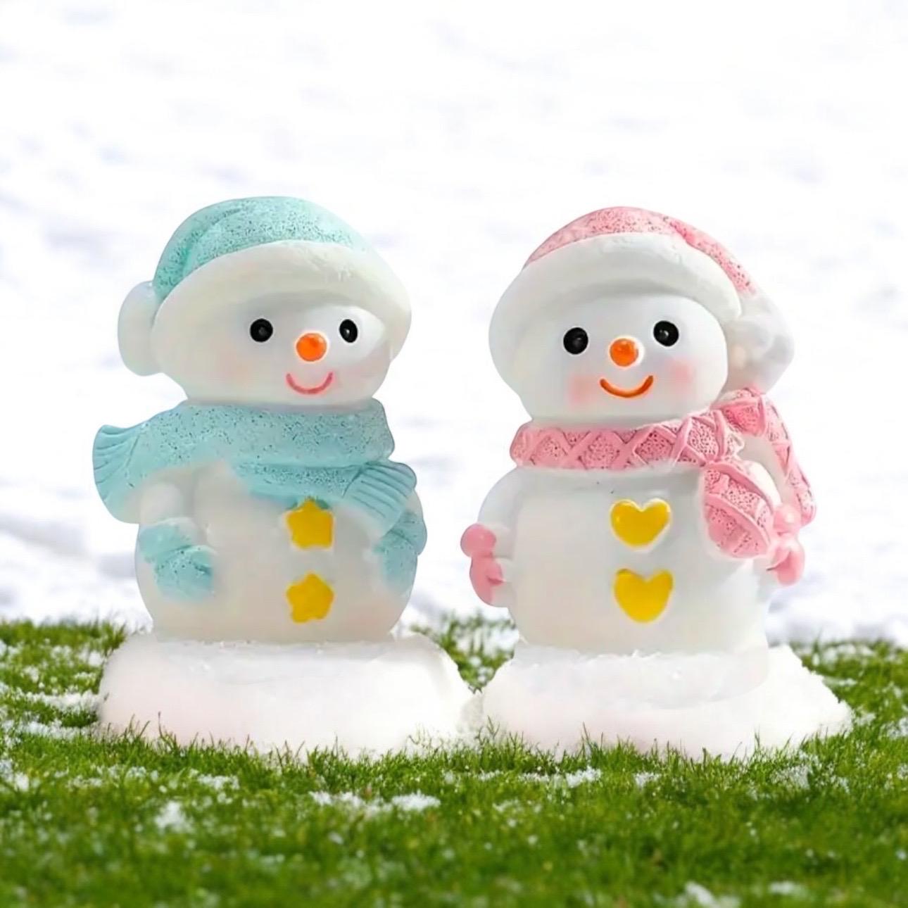 Two snowman figurines with colorful hats and scarves on a grassy background.