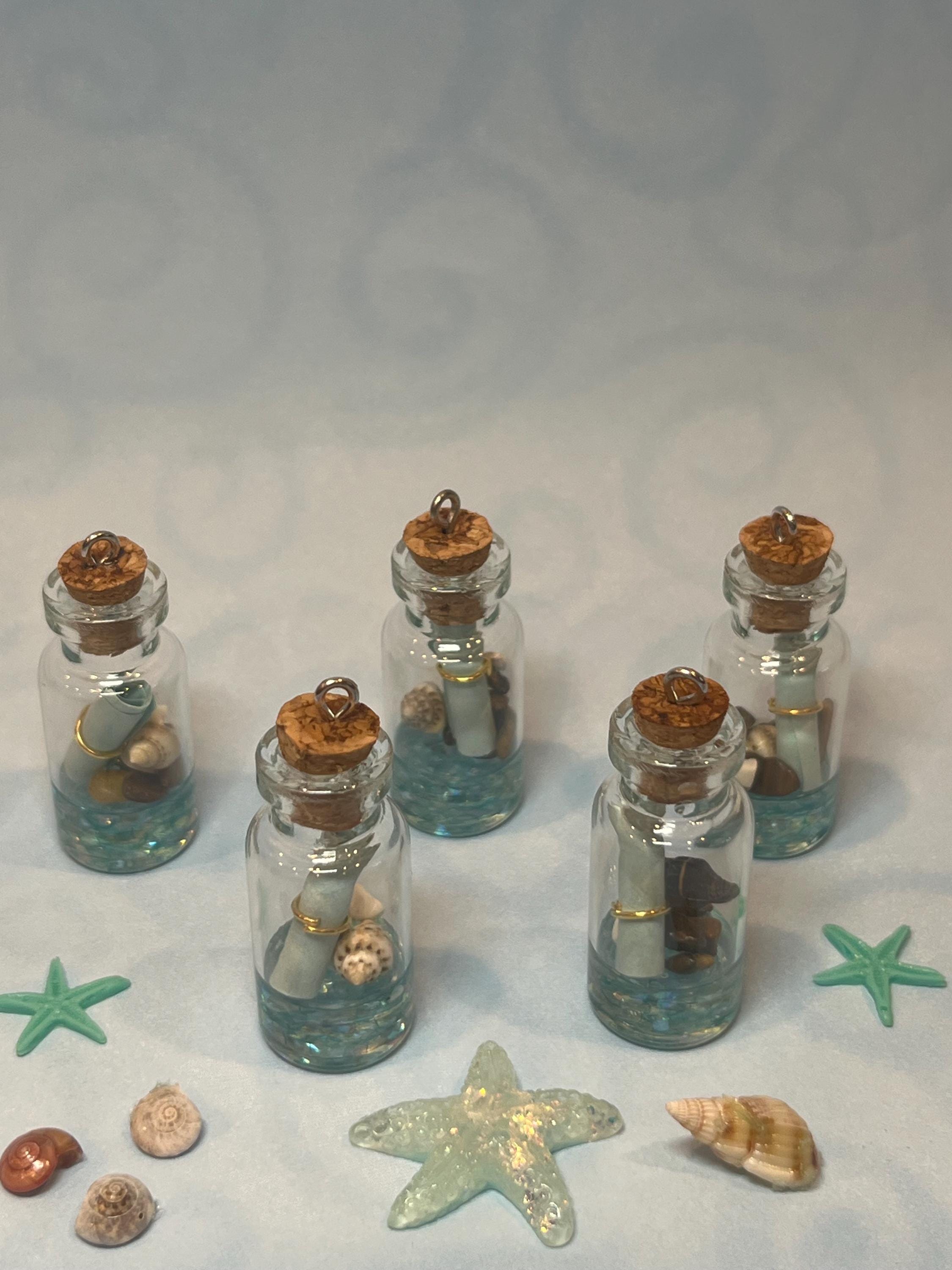 Set of small glass jars with cork lids containing seashells and starfish on a light background