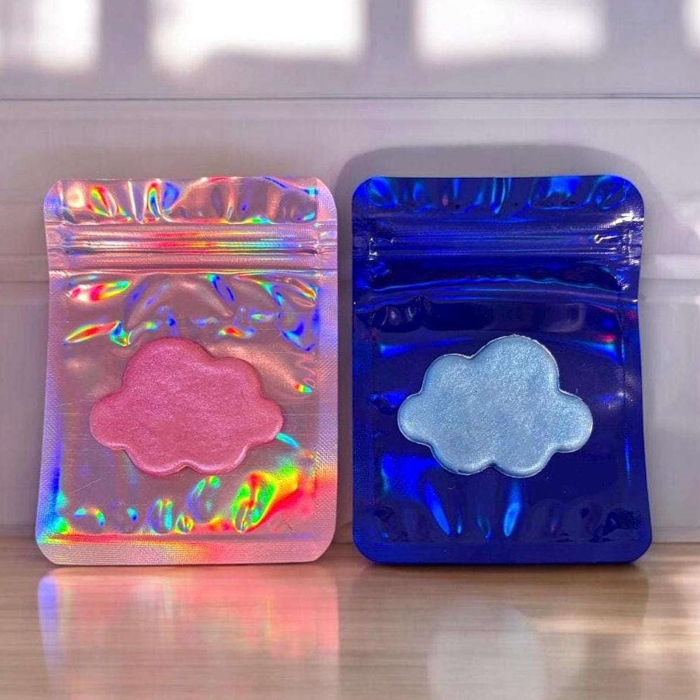 Two colorful foil packages with pink and blue cloud designs on a reflective surface.