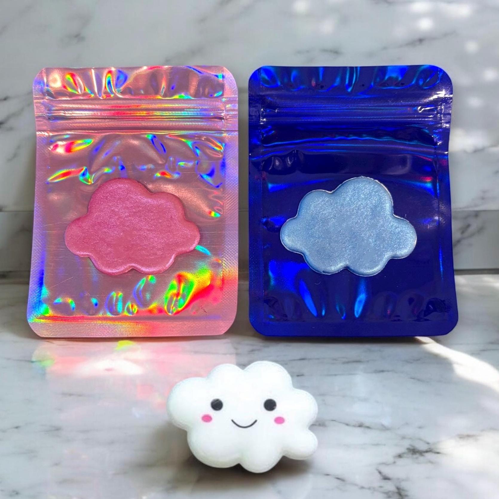 Two cloud-shaped objects in colorful packaging on a marble surface