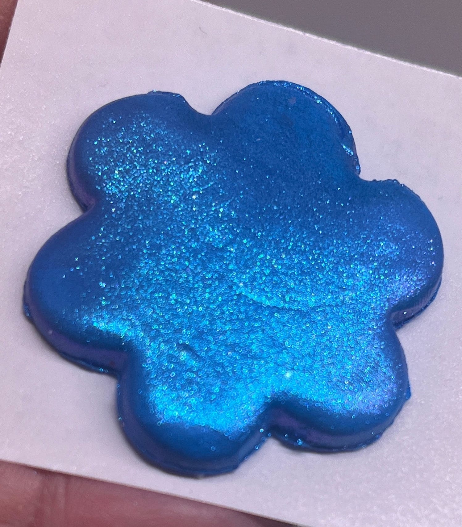 Blue glittery flower-shaped object on a white background