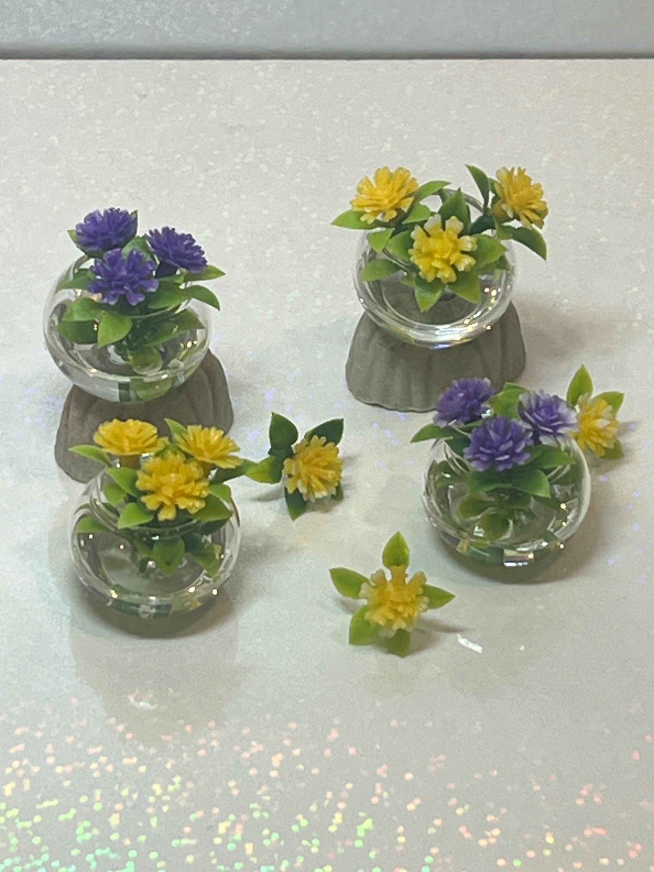 Set of small glass containers with artificial plants on a reflective surface