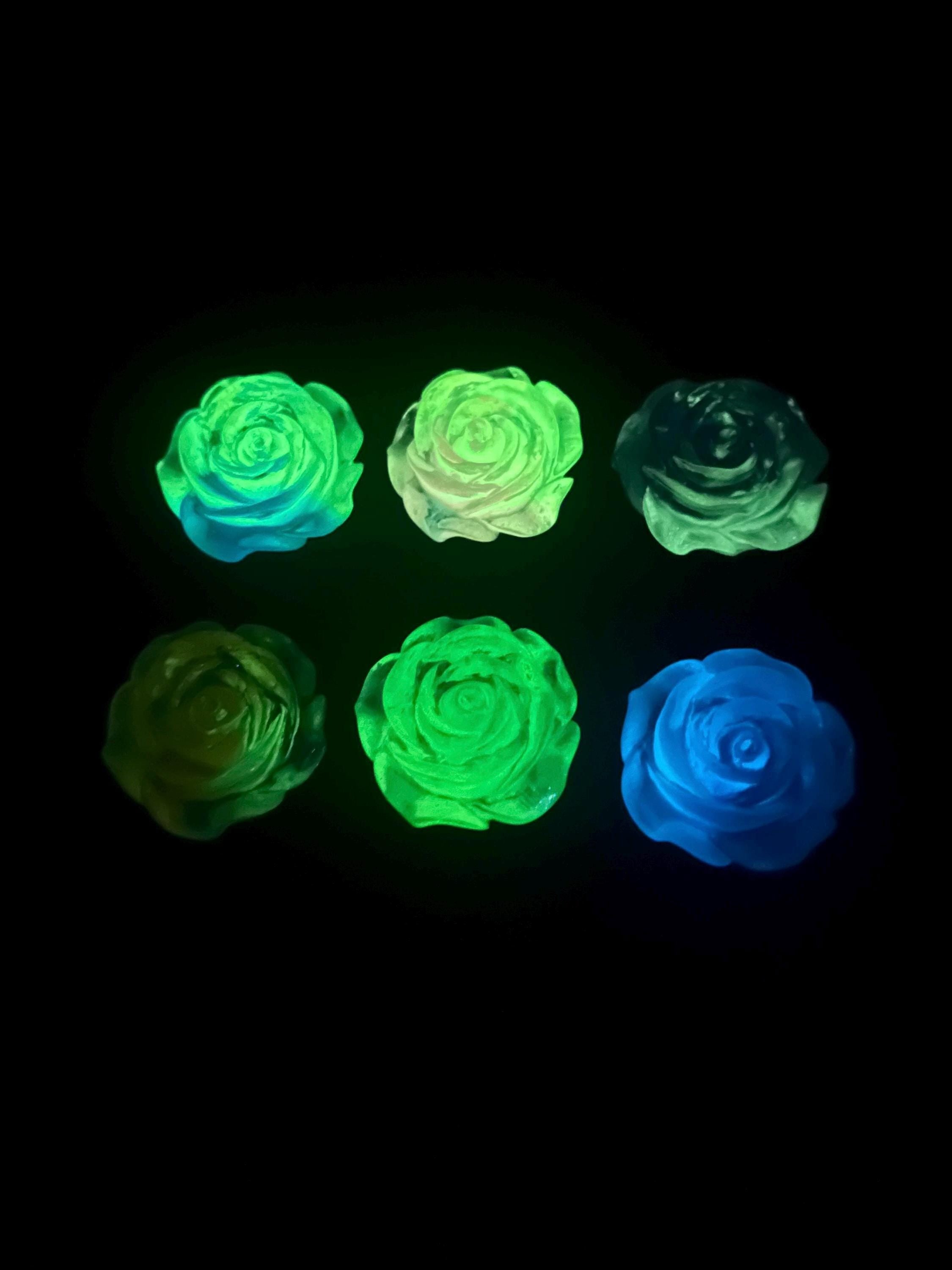Glowing green and blue rose-shaped objects on a black background