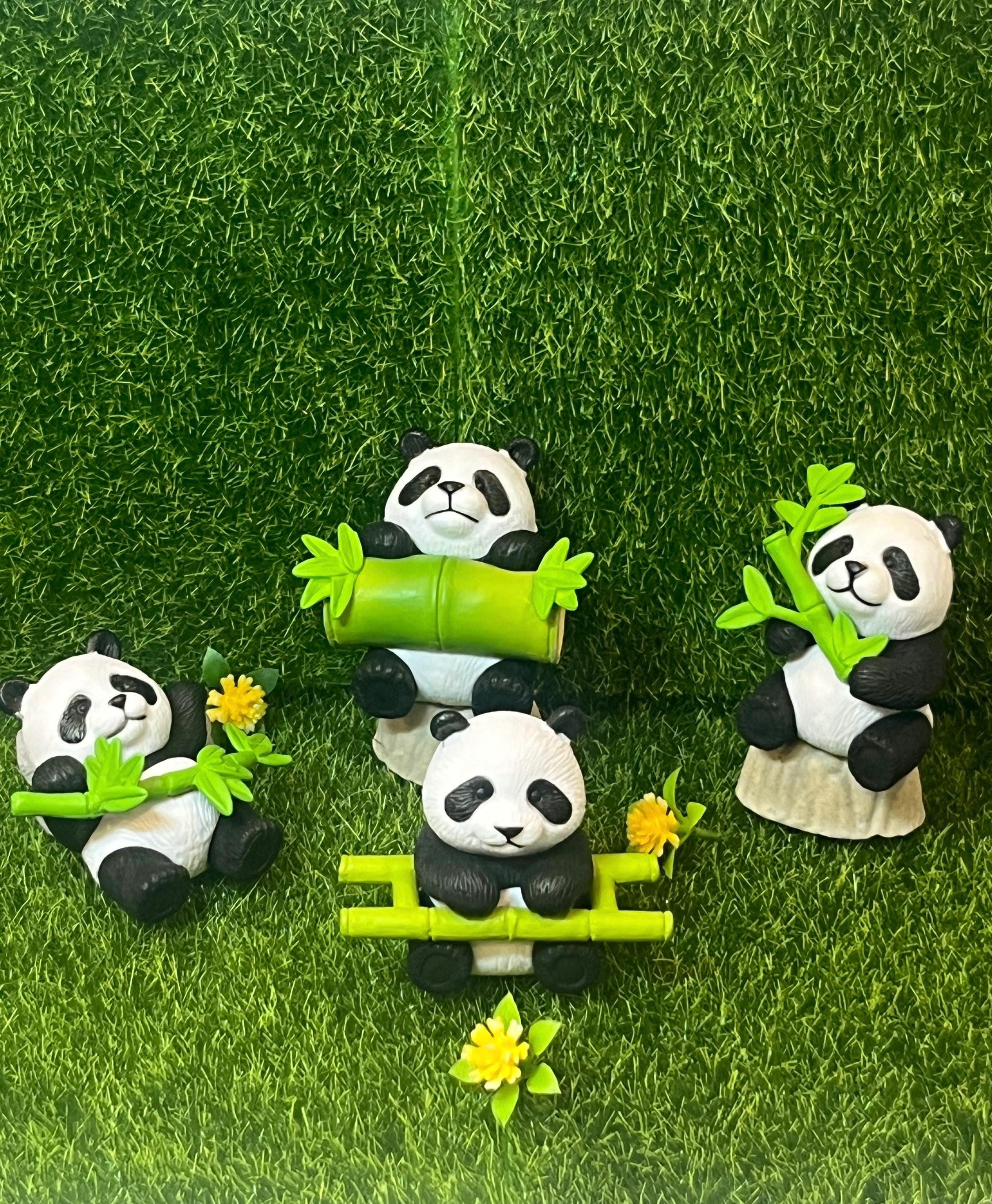 Set of panda figurines with bamboo on a grassy background