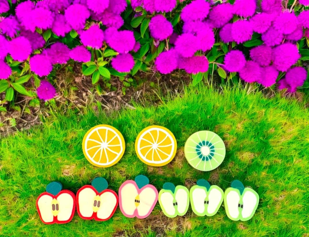 Fruit-shaped cookies on grass with purple flowers in the background