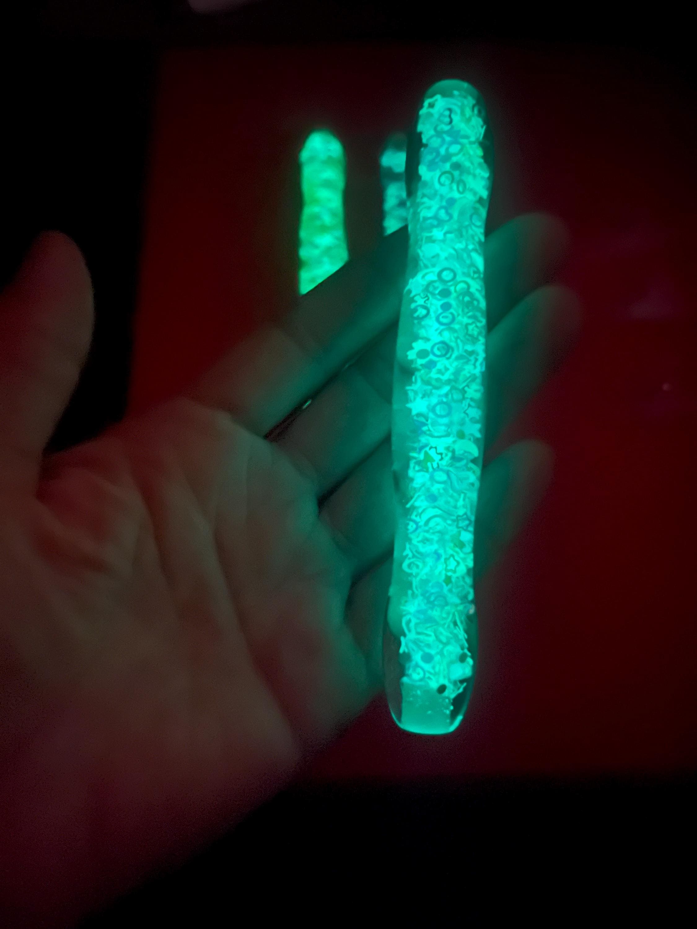 Glow sticks held in a hand against a dark background