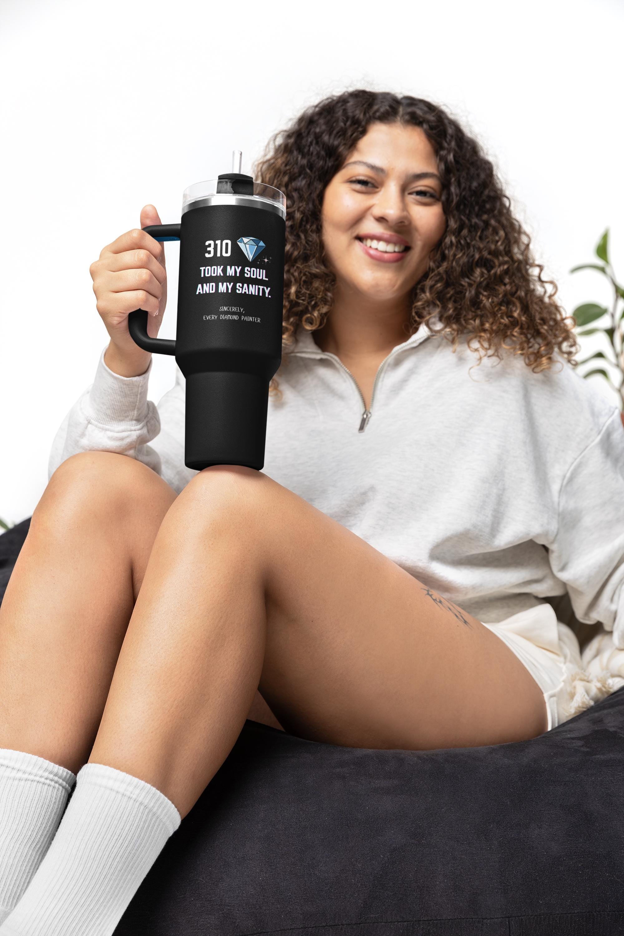 Woman holding a black mug with text, sitting on a couch.