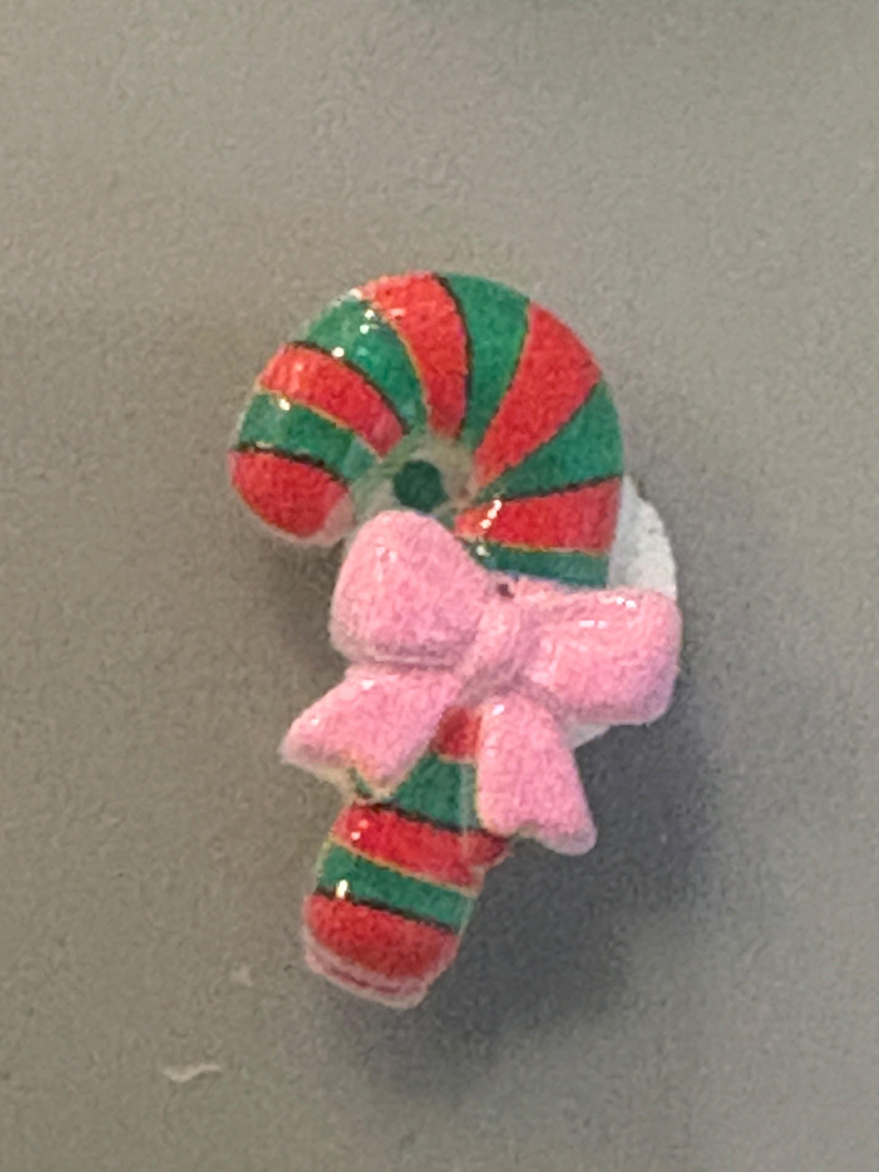 Decorative candy cane with a pink bow on a gray background