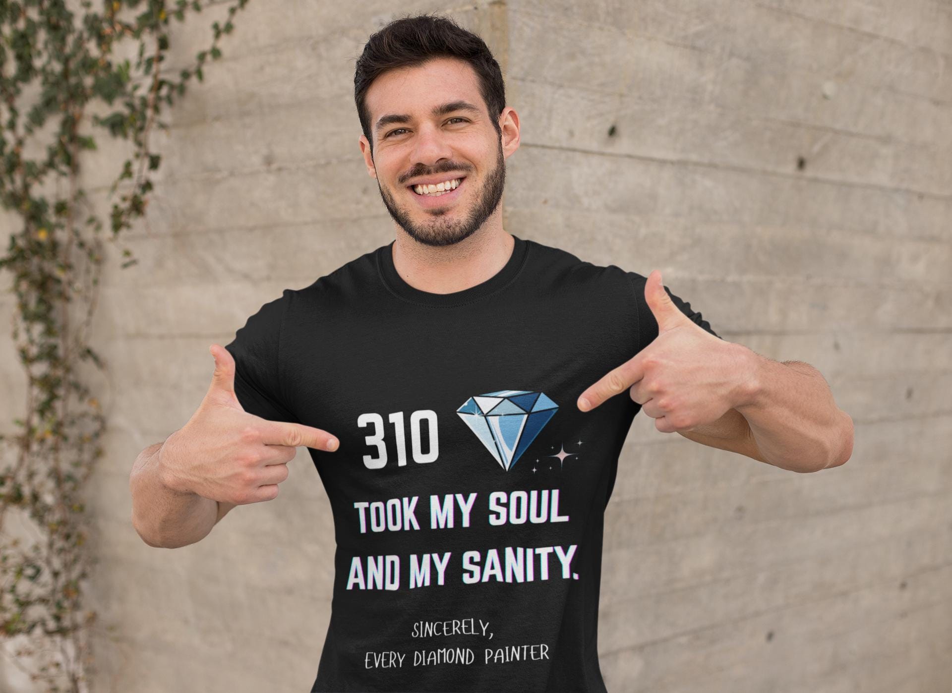 Man wearing a black t-shirt with text and a diamond graphic, pointing at the shirt.
