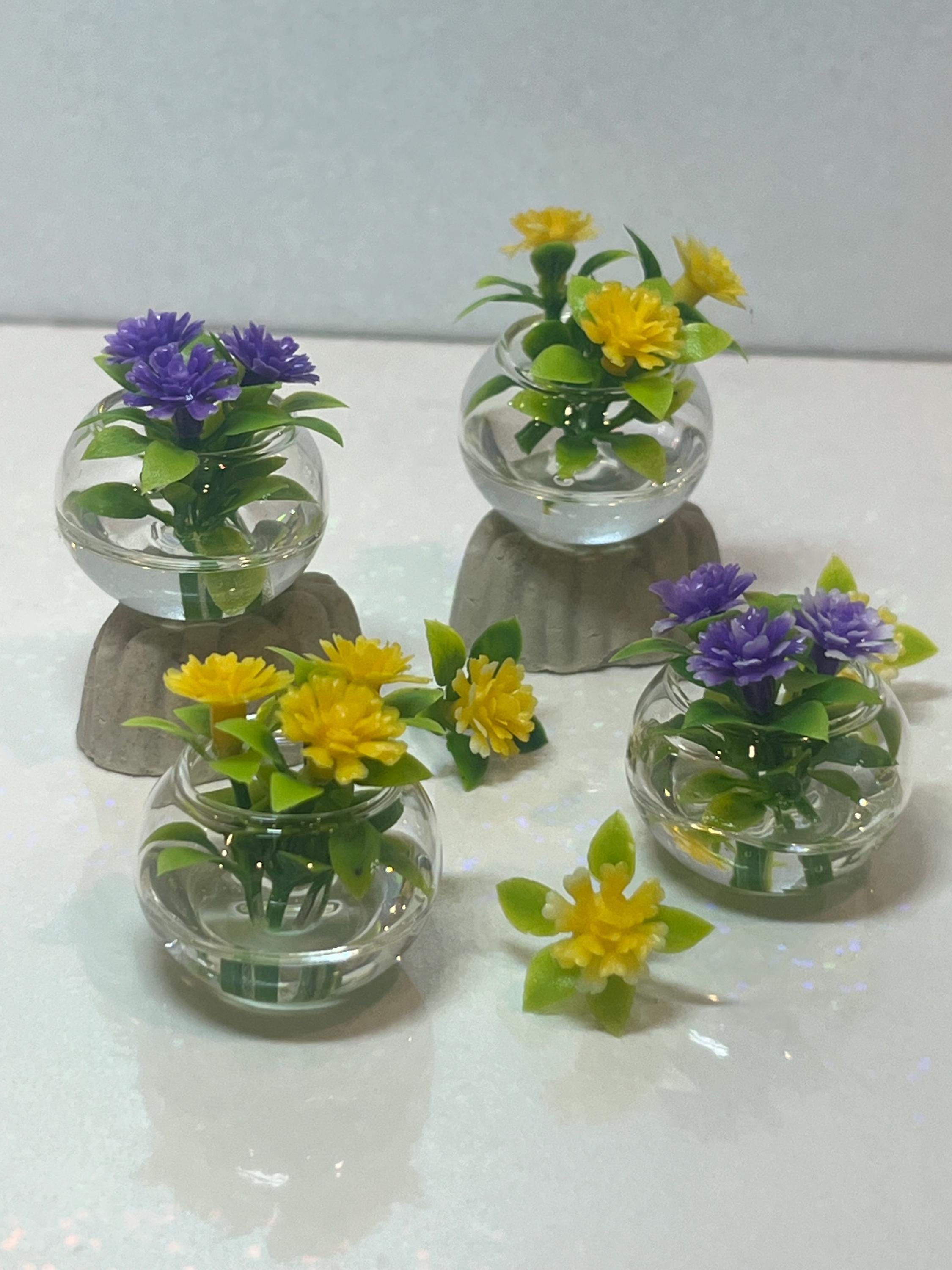 Set of small glass containers with artificial plants on a white surface