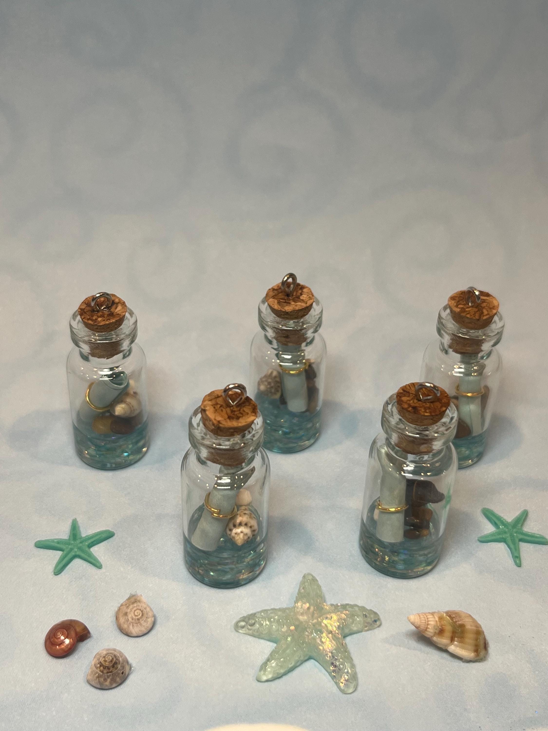 Small glass bottles with cork lids containing seashells and starfish on a light gray background