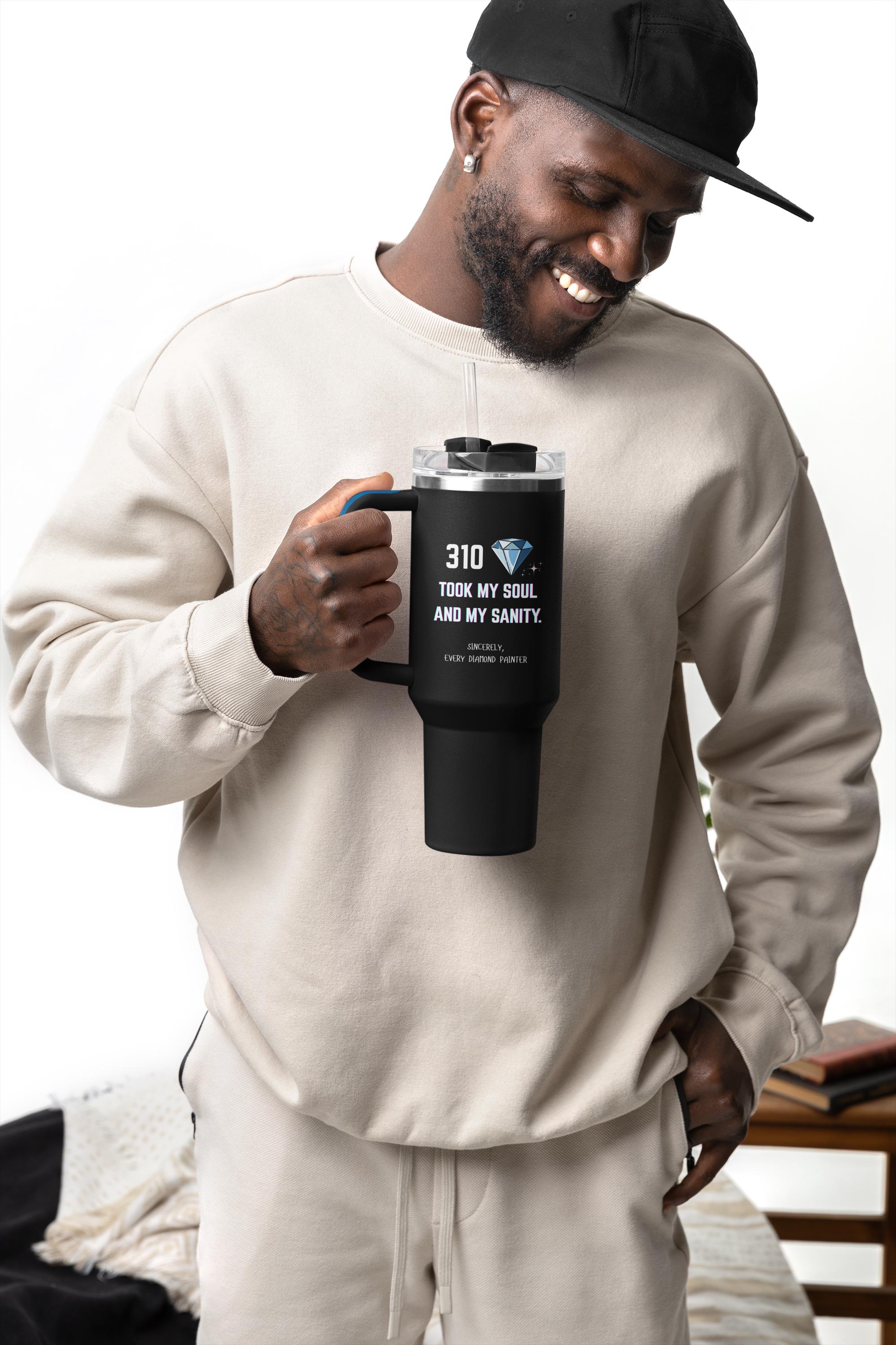 Man holding a black mug with text, wearing a beige sweatshirt and cap.