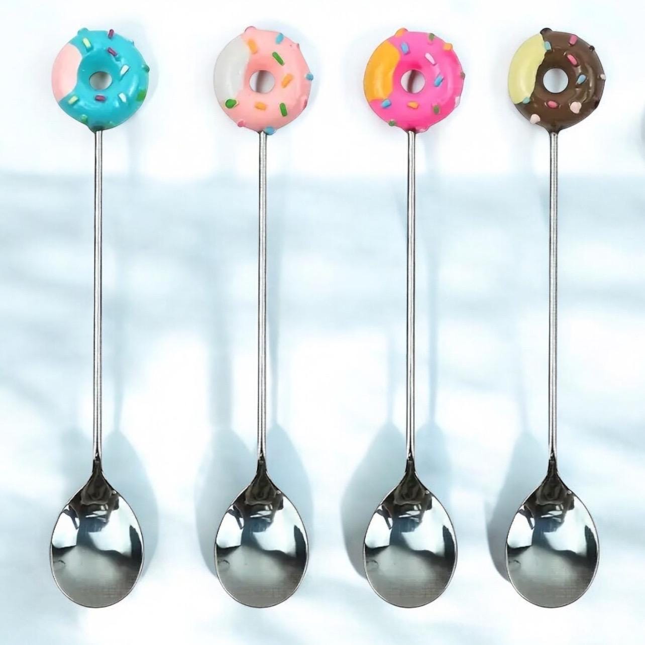 Four spoons with colorful donut-shaped ends on a light blue background