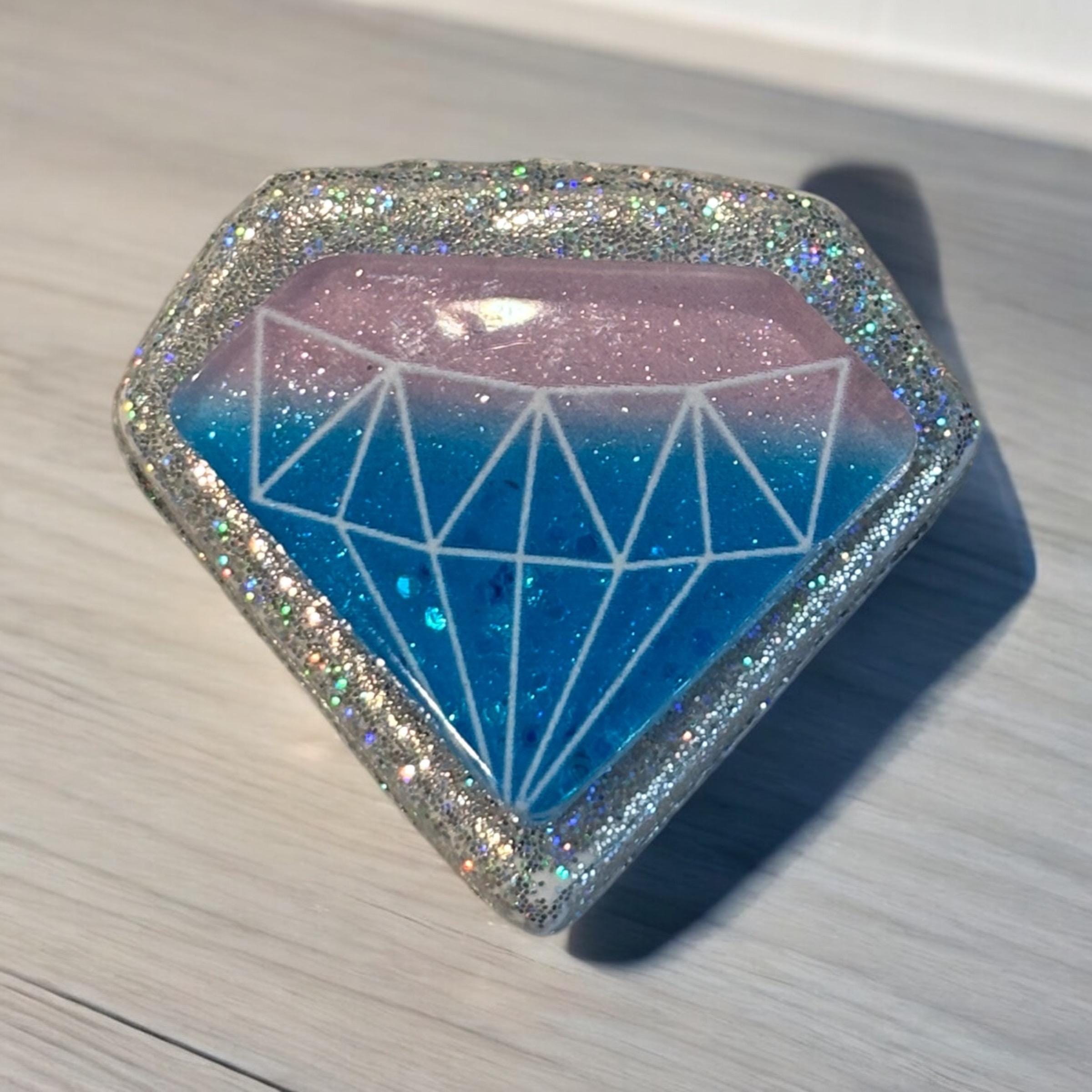 Diamond-shaped object with blue and pink gradient on a light wooden surface