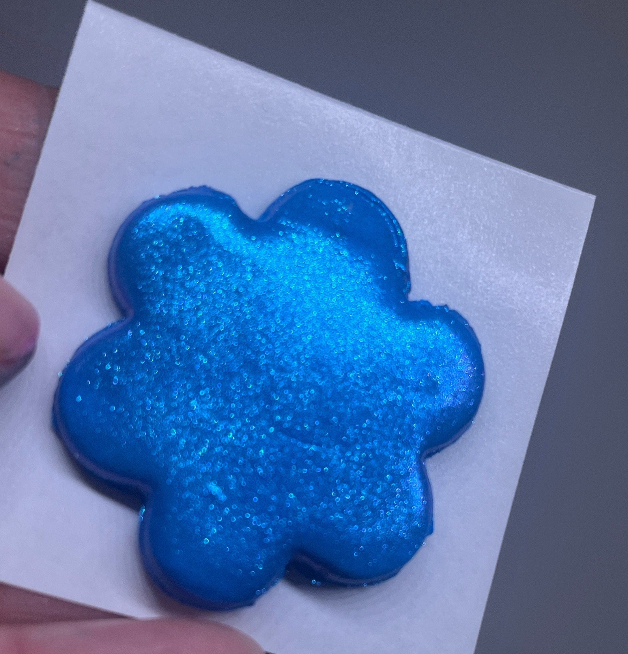 Blue glittery flower-shaped object on a white background
