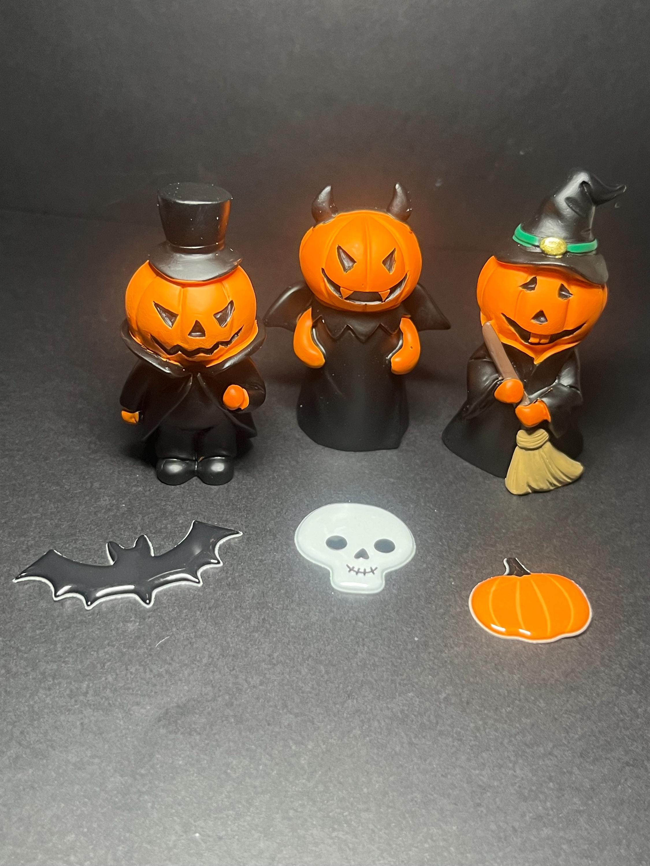 Three Halloween-themed figurines on a dark surface with decorative items.