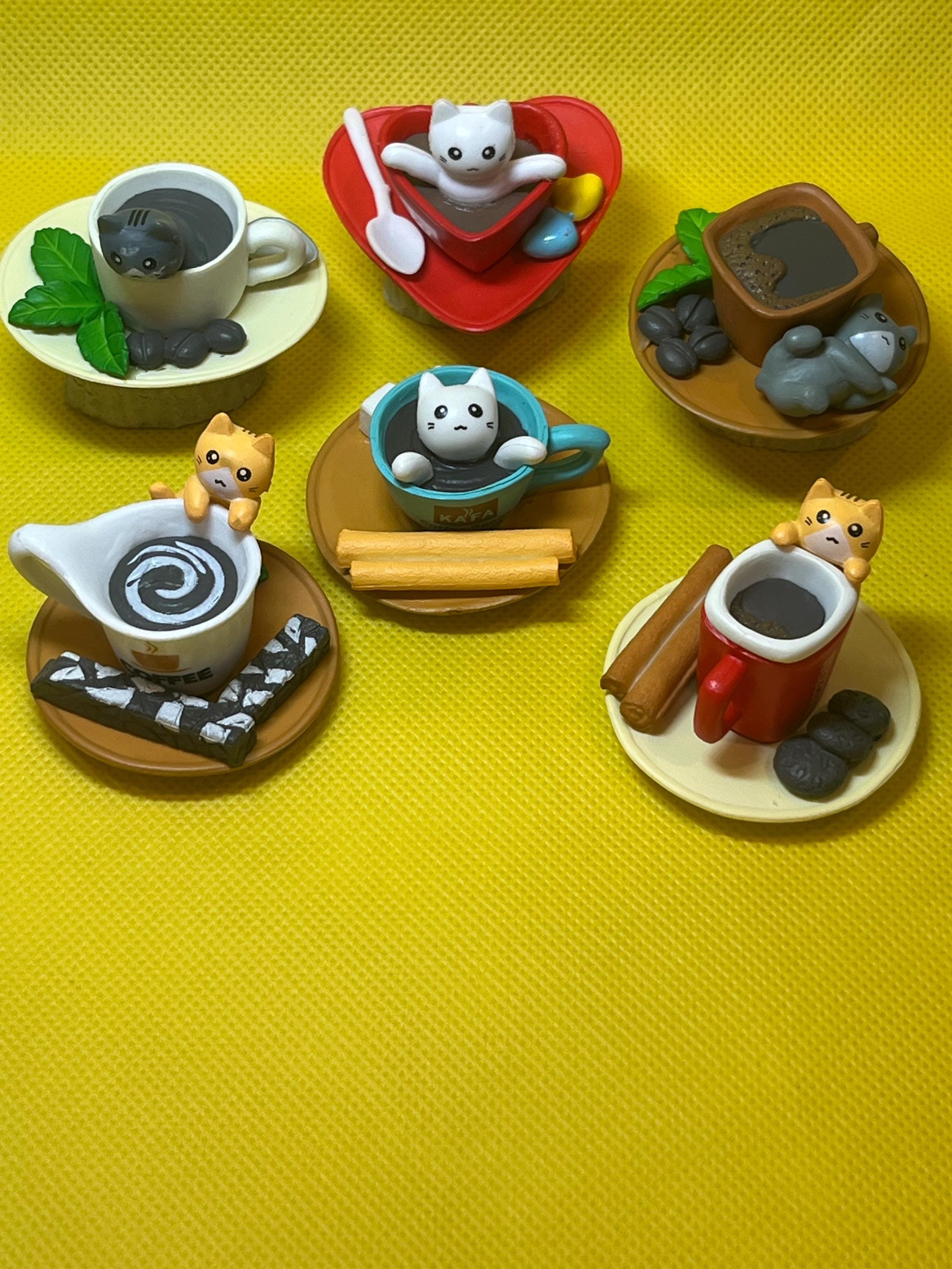 Set of miniature figurines on a yellow surface, featuring animals around a coffee setup.